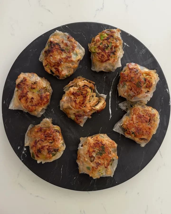 Eleven chicken and vegetable rice paper ravioli on a dark marble board, from above